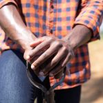 Front view mid section of an African American man standing in a farming field leaning on the handle of a spade. Family enjoying time at home, lifestyle concept